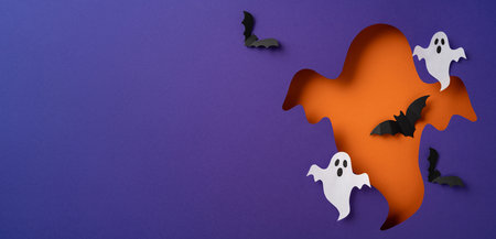 Creative depiction of Halloween with vibrant paper cutouts of ghosts and bats on colored background