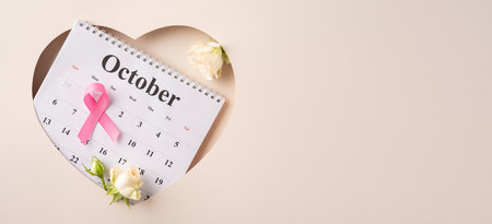 Pink ribbon on October calendar symbolizing breast cancer awareness, adorned with fresh white rosesの写真素材