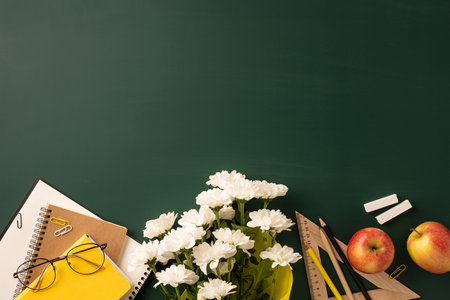 Teacher's desk decorated with flowers, apples, notebooks, and stationery on a green background conveying celebration, learning, organization, and gratitude for Teacher's Dayの写真素材
