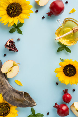 Rosh Hashanah Jewish New Year vertical composition with apples, honey, pomegranate, and shofar on a pastel blue surfaceの写真素材