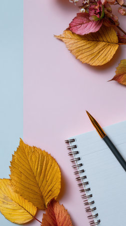 Notebook and pen placed with colorful autumn leaves on a pastel background. Generated A.I.の素材