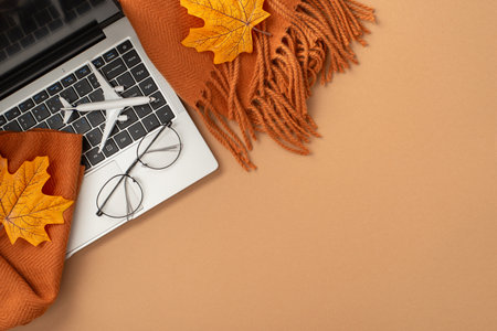 Flatlay showcasing a laptop adorned by autumn-themed objects including leaves and a scarf, symbolizing seasonal work and travel vibesの写真素材