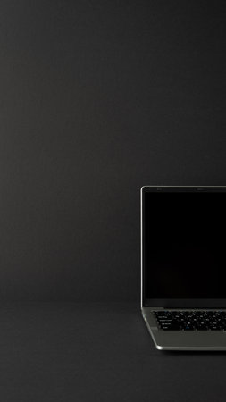Image of an open vertical laptop placed on a sleek dark-colored surface, symbolizing technology and productivity in a professional and modern workspace with minimalistic designの写真素材