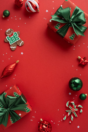 Vibrant vertical Christmas scene featuring wrapped presents, ornaments, a gingerbreadman, candy canes, and glittering confetti on a red background for holiday and New Year promotionsの写真素材