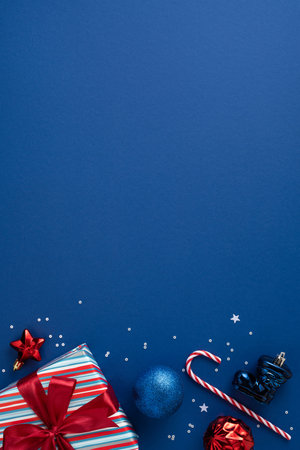 Wrapped vertical gifts and blue backdrop create a festive mood for Christmas and New Year, with ornaments, candy cane, ribbons, and confetti suggesting celebration and joyの写真素材