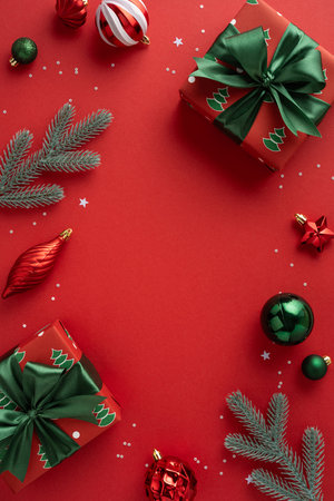 Vibrant vertical red background wrapped features gifts with green ribbons, pine branches, and festive ornaments, creating a cheerful scene perfect for Christmas and New Year greetingsの写真素材