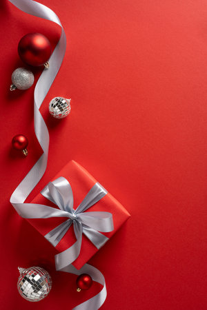Vertical festive scene with a red wrapped gift, silver ribbon, and ornaments, capturing Christmas and New Year celebration, warmth, sparkle, and holiday moodの写真素材