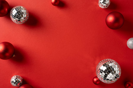 Vibrant red backdrop featuring mirrored disco balls and red ornaments, perfect for Christmas and New Year promotions, greeting cards, and seasonal product shoots with glamorous holiday flairの写真素材