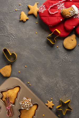A vertical cozy Christmas baking scene with star and snowflake shapes, a metal mold, cookie cutter, and red mittensの写真素材