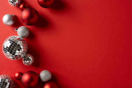 Vibrant red backdrop with metallic disco balls and Christmas ornaments evokes a festive mood for the holiday season. Ideal for greeting cards, promotionsの写真素材