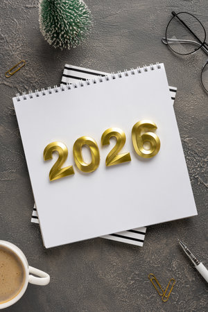 Vivid desk scene with golden year numbers on a notebook, coffee cup, and office accessories,...