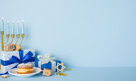 A Hanukkah scene featuring a lit menorah, blue and white gifts, dreidels, gelt coins, and a festive mood celebrating lights, tradition, and faithの写真素材