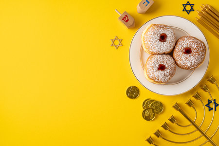 A festive Hanukkah scene featuring powdered sugar donuts, a lit menorah, and a colorful dreidel on a bold yellow background. Ideal for greeting cards, holiday posts, and celebration themesの写真素材