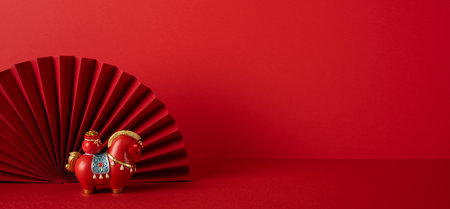 Side view of a festive red Chinese New Year display featuring a decorative fan and a toy horse, capturing celebration, luck, and tradition through vibrant color and cultural charmの写真素材