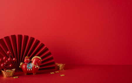 Side view of red decor and festive items, including fan, horse figurine, coins, and gold accents, presenting a Chinese New Year scene of luck and prosperityの写真素材