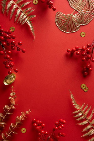 Vibrant vertical red background frames decorative gold leaves berries and coins celebrating Chinese New Yearの写真素材