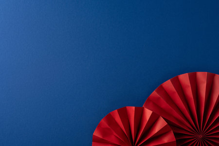 Red paper fans decorate a blue backdrop signaling Chinese New Year celebration and greeting. The image conveys festive energy, cultural tradition, and joyful greetingの写真素材