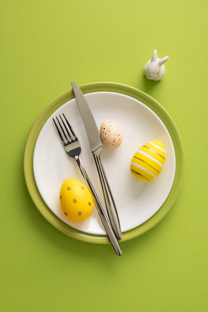 Happy Easter vertical table setting featuring yellow decorative eggs, stainless steel cutlery and a...