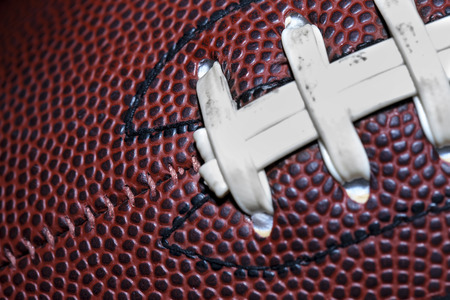 close up of an american football against a black background