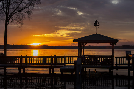 A colorful sunset over water with a pier in the foregroundの写真素材
