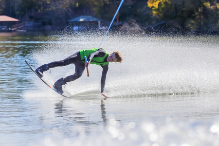A young athlete wake boards on a body of waterの写真素材