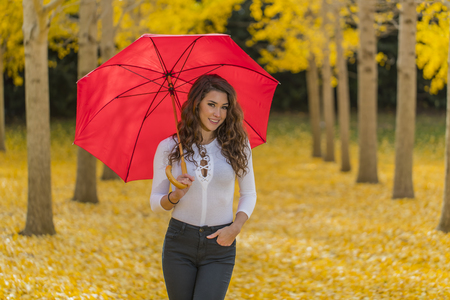 A beautiful brunette model with yellow fall foliageの写真素材