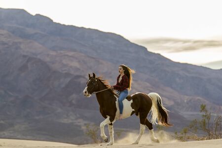 A female model riding her horse through the Mohave Desertの写真素材