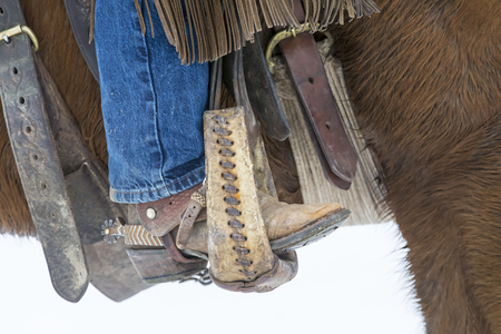 Cowboys round up a herd of horses as they're running through the snow in the mountainsの写真素材