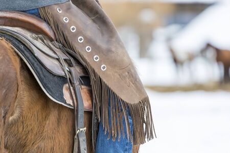 Cowboys round up a herd of horses as they're running through the snow in the mountainsの写真素材