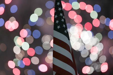 The Stars and Stripes wave through the night sky with fireworks in the backgroundのeditorial素材
