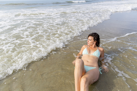 A beautiful brunette model enjoys a day by the beachのeditorial素材