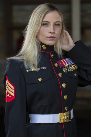 A blonde model posing in military uniform in an outdoor environment