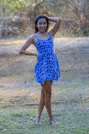 A beautiful hispanic brunette model enjoying a hot summer day while running through waterの写真素材