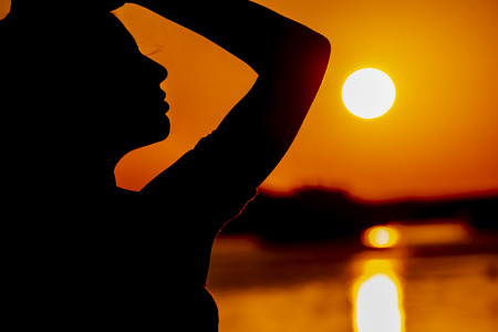 A beautiful hispanic brunette model enjoying the morning sun at sunriseの写真素材