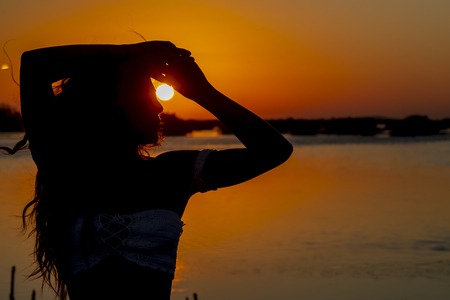 A beautiful hispanic brunette model enjoying the morning sun at sunriseの写真素材