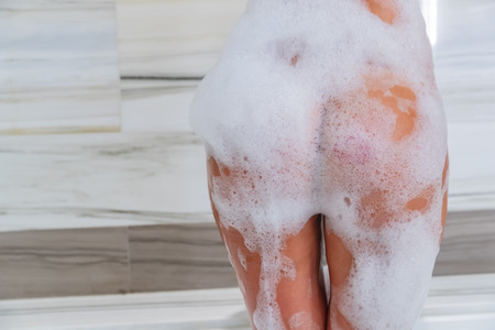 A beautiful blonde model getting ready to take a bath while drinking champagne