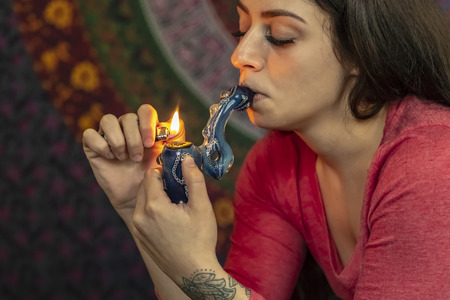 A beautiful brunette model smokes marijuana in the privacy of her own homeの写真素材