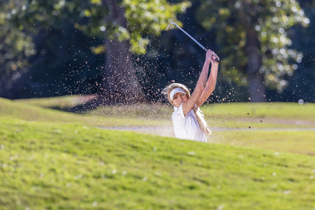 A beautiful blonde model enjoying a round of golf on a sunny dayの写真素材