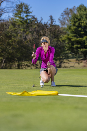 A beautiful blonde model enjoying a round of golf on a sunny dayの写真素材