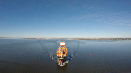 A cargo ship steams towards the open ocean out of a harborの写真素材