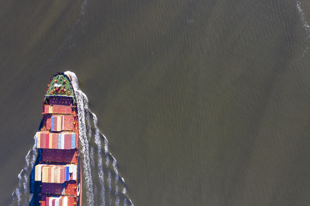 A cargo ship steams towards the open ocean out of a harbor