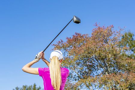 A beautiful blonde model enjoying a round of golf on a sunny dayの写真素材