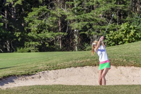 A beautiful blonde model enjoying a round of golf on a sunny dayの写真素材