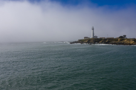 Aerial view of a lighthouse off the California Coast as fog settles inのeditorial素材