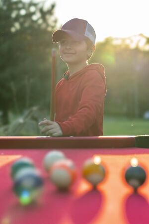 A small young boy plays pool in an outdoor environmentの写真素材
