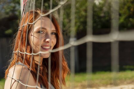 A redhead fitness model preparing to play volleyballの写真素材