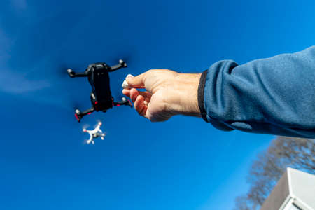 A group of drones fly through the air against a blue skyのeditorial素材
