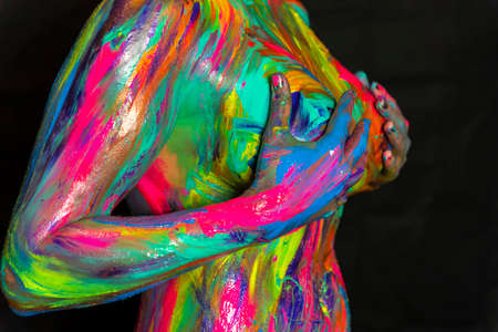 A naked woman is painted with colorful paint in a home environmentの写真素材