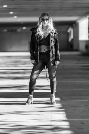 A gorgeous blonde model poses in a parking deck on an autumn dayの写真素材
