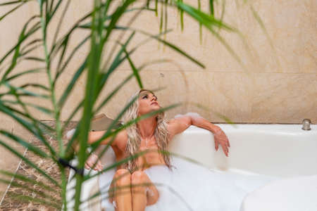 A gorgeous blonde model poses while taking a bath